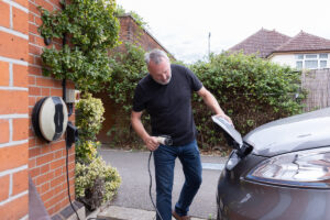 Man putting charging cable into electric car