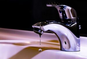 Photo of a tap with water droplets coming out of it.